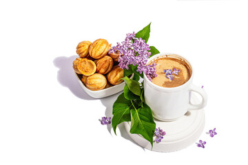 Cup of coffee and cookies in the shape of walnuts with cream filling isolated on a white background