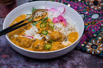 Vegetarian mushroom korma and koftas over basmati rice in white bowl