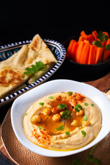 Healthy Food concept homemade hummus with flatbread pita and carrots on black background with copy space