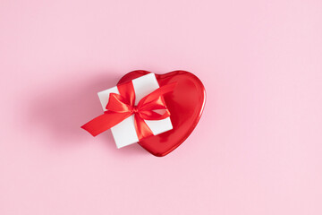 Valentine's Day background. Red box in shape of heart and gift box with red bow on isolated pink background. Valentine's day concept. Flat lay, top view, copy space