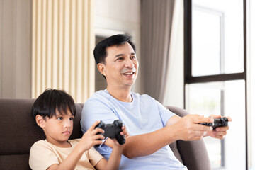 Happy father dad and son play video game station with control game by remote joystick technology...