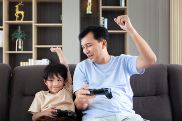 Happy father dad and son play video game station with control game by remote joystick technology for family entertainment activity during weekend