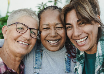 Happy multiracial senior women having fun together outdoor - Elderly generation people hugging each...