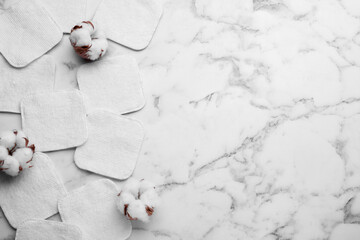 Flat lay composition with many clean cotton pads and flowers on white marble table. Space for text
