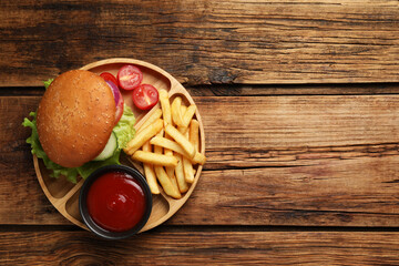 French fries, tasty burger and sauce on wooden table, top view. Space for text