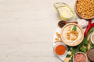 Delicious hummus with chickpeas and different ingredients on white wooden table, flat lay. Space for text