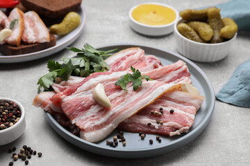 Slices of tasty pork fatback with spices on grey table, closeup