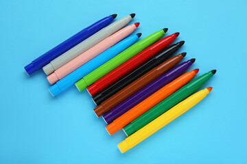 Many different colorful markers on light blue background, flat lay