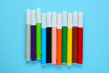 Many different colorful markers on light blue background, flat lay