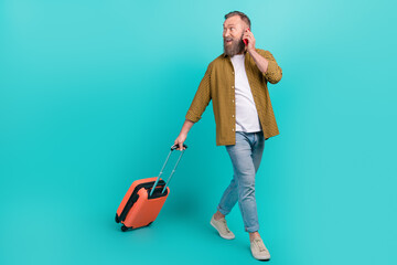 Photo of attractive senior businessman walk look empty space reserving booking taxi hotel hold baggage isolated on cyan color background