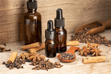 Aromatic seeds essential oil still life. Amber glass bottle Cinnamon, anise, peppercorn, clove oil...