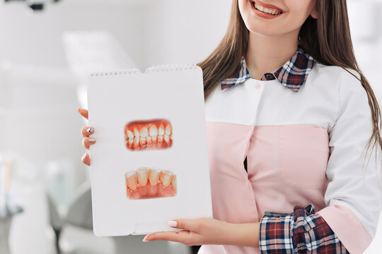 Young female dentist showing picture of teeth in her office.