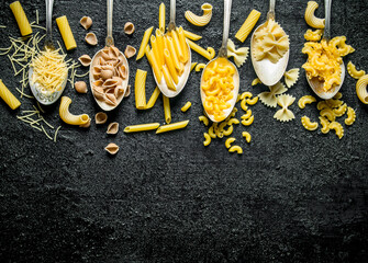 The range of different types of dry pasta in spoons.