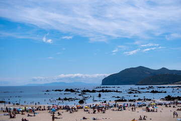 Obraz premium Beach coast with a view over the sea with some mountains in the background and rocks in the water.