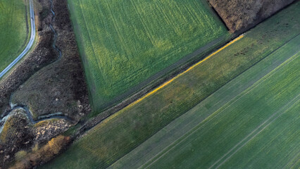 Aerial view of agriculture fields. Geometric agricultural fields showing green meadow and plowed fields taken by drone.