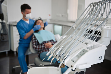 Dental instruments with the dentist treating teeth of patient on background.