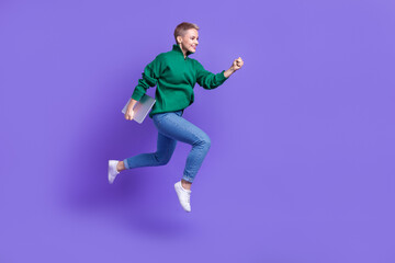 Fototapeta na wymiar Full length photo of shiny cute woman dressed green pullover jumping running holding device empty space isolated purple color background
