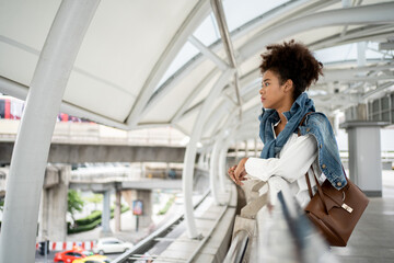 Pretty beautiful black woman waiting the train at the train station for travel in summer. Feeling lonely when travel alone.