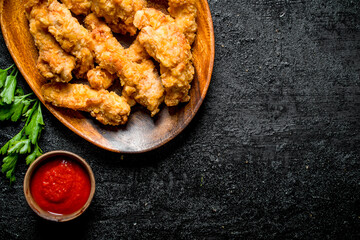 Chicken strips on a plate with parsley and sauce.