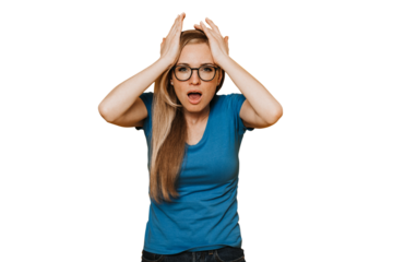 Young red haired woman in glasses, blue t-shirt and jeans, with open mouth, holding her head because of headache and many problem, upset against transparent background. Mistake, failure.
