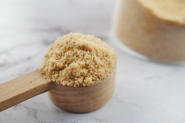 coconut sugar on a wooden spoon on white 