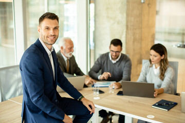 Young businessman standing in front of his coleagues in the office