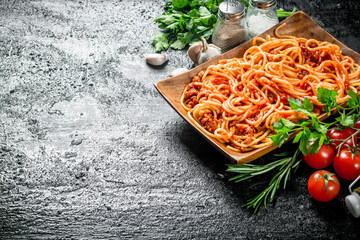 Spaghetti with Bolognese sauce on a plate with herbs, tomatoes and garlic.