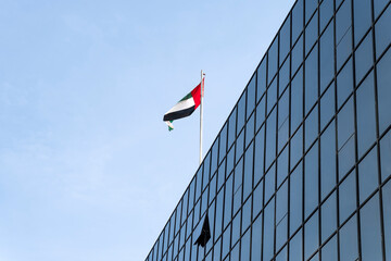 the flag of the UAE on a blue sky background. Flag waving at the top of the modern building,...