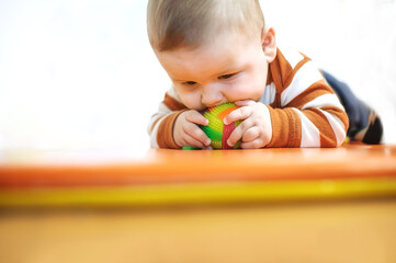 Baby plays with toys. Close-up view of cute baby boy lies on its stomach and play with toy. Playground for babies