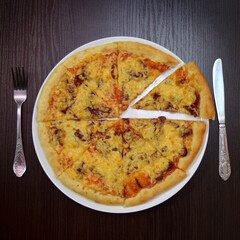 Delicious fresh cheese pizza with mushrooms, smoked sausages on black table, white plate, fork, knife nearby, top view