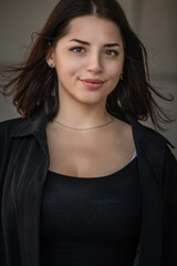 Dramatic close-up portrait of a dark-haired beautiful young girl on a gray background.