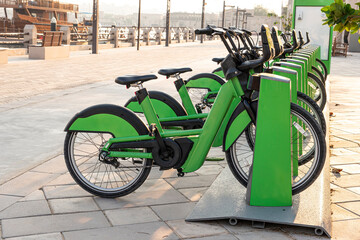 electric bicycles for rent are green in parking lot in the city center on the street. Eco-friendly...