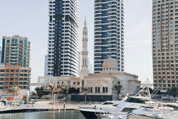 Photo of the imposing large Mohammed Bin Ahmed Al Mulla Mosque between the high rise buildings of the Dubai Marina on the Al Emreef Street bridge.