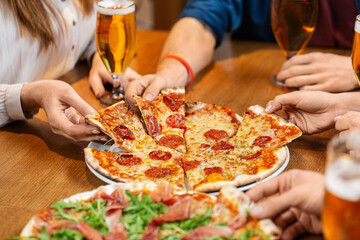 leisure, food and drinks, people and holidays concept - close up of friends eating pizza and drinking beer at restaurant or pub