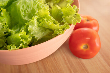 bowl with tomato and lettuce salad on wooden background