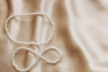 Fototapeta na wymiar Pearl bijouterie beads on silk texture background.