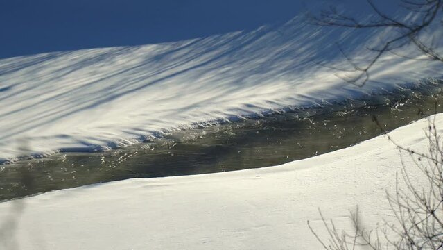 Frozen river with water running in Northern Ontario on a sunny winter afternoon.