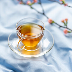 Spring morning breakfast concept with a cup of green tea on the blue bed sheets. Close up