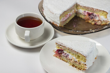 Homemade cake with a cup of tea on a white background. Slice of homemade white cake