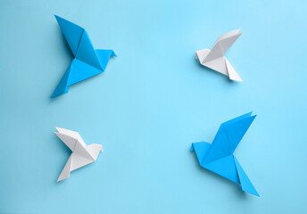 Origami art. Colorful handmade paper birds on light blue background, flat lay. Space for text