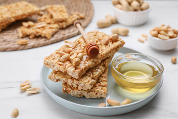Delicious peanut bars (kozinaki) and dipper with honey on white marble table, closeup
