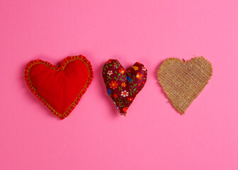 Three fabric hearts on a magenta background. Horizontal arrangement. Flat lay