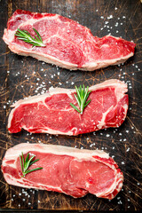 Raw marbled beef steaks with salt and aromatic spices.