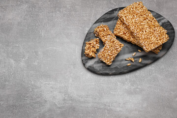 Board with puffed rice bars (kozinaki) on grey table, above view. Space for text