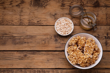Puffed rice pieces (kozinaki) on wooden table, flat lay. Space for text