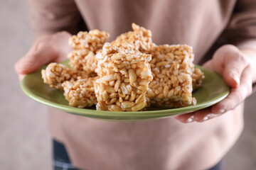Woman holding plate with puffed rice pieces (kozinaki), closeup