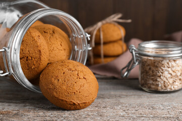Delicious oatmeal cookies and flakes on wooden table, closeup. Space for text