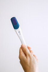 Positive pregnancy test with two strips in the hand. Blue color background. Positive result. White background.