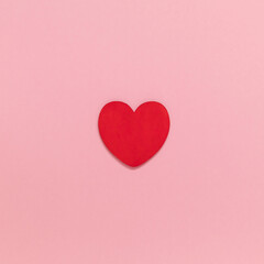 Red wooden heart in the center of the pink background. Valentines day concept. Top view. Copy space.