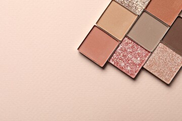 Different beautiful eye shadows on beige background, flat lay. Space for text